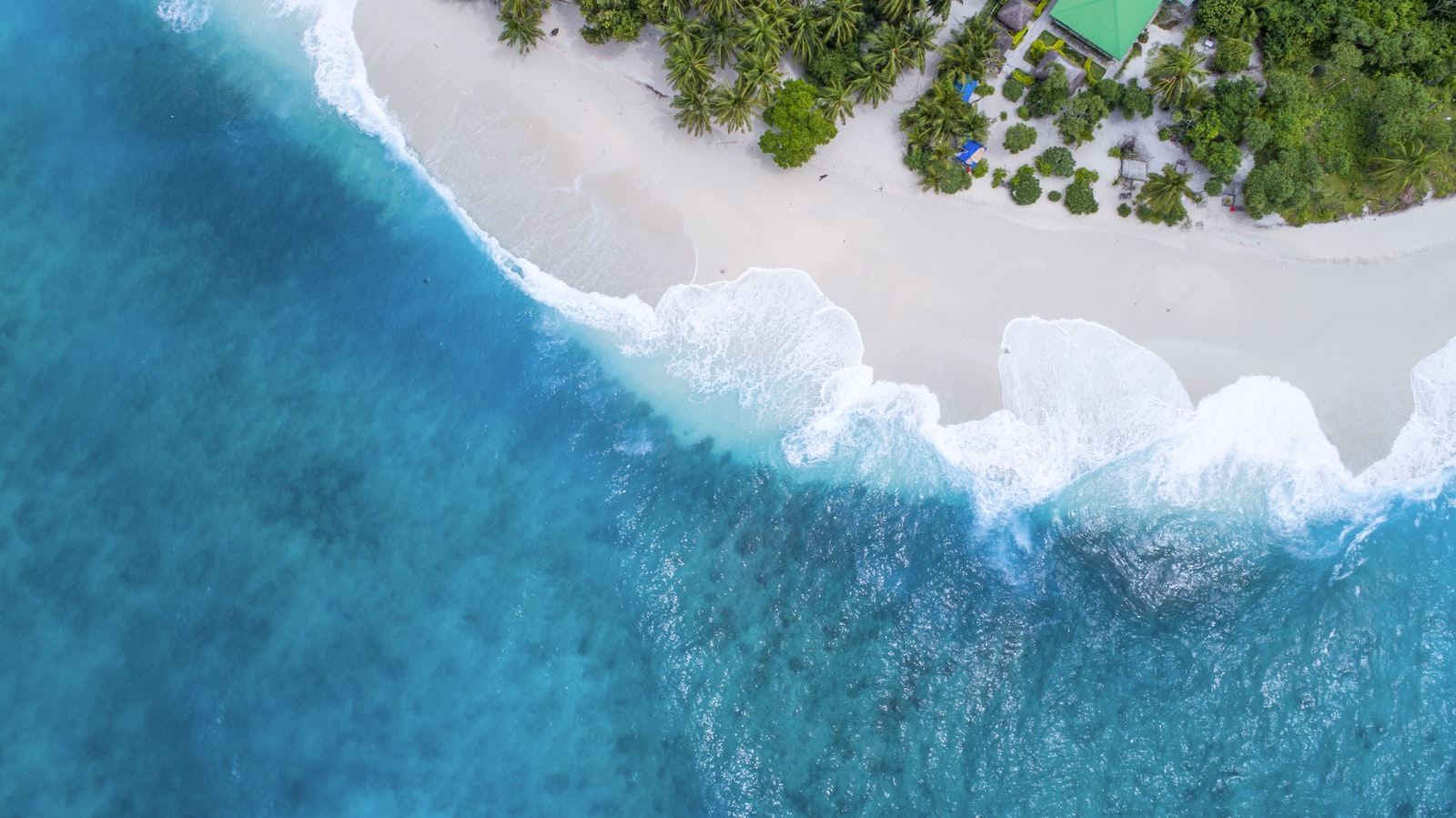 A single sandy island ringed by turquoise shallows seen from above