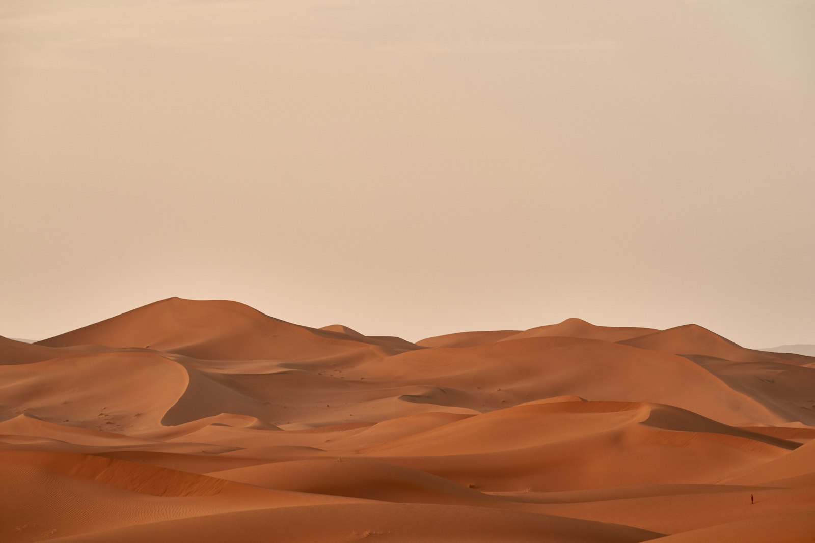 A minimalist desert retreat at dusk with low lamplight against the dunes